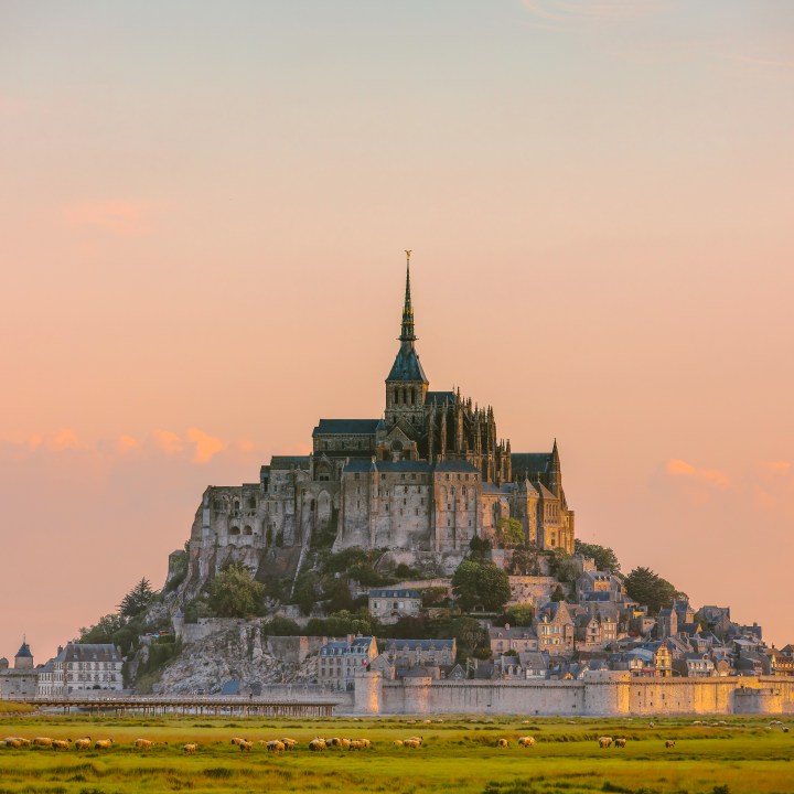 An enchanting view of Mont Saint-Michel during the early morning hours near Rennes, Brittany, France. This famous tidal island in Normandy is bathed in the soft light of dawn. Mont Saint-Michel, an island commune with ancient strategic fortifications and a historic monastery, stands majestically against the serene backdrop of the morning sky.