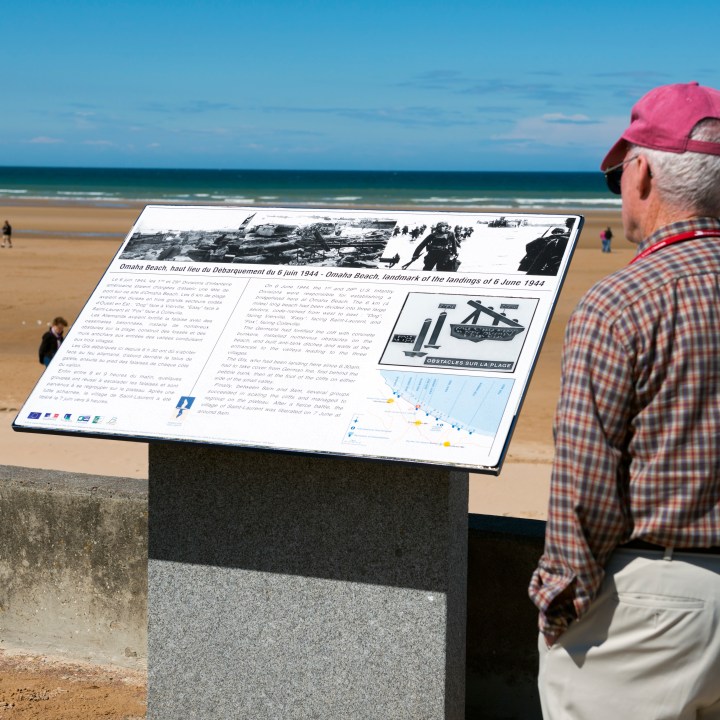 Saint-Laurent-sur-Mer, France - May 13, 2014: A man reads an information panel about the D-Day landings here at Omaha Beach in Normandy, France